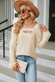 Cream textured open shoulder blouse with keyhole neckline and long sleeves.