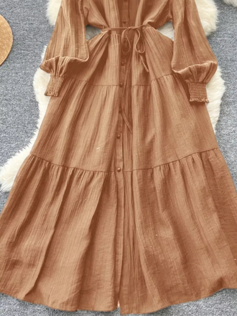 Caramel textured tiered long sleeve button-down midi dress with cinched cuffs and tie waist.