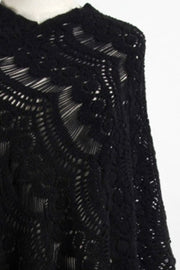 Black crochet poncho with open knit pattern and fringe detail