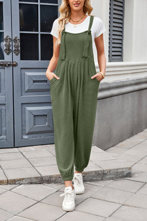 Olive green corduroy overalls with barrel leg and tie straps, worn with a white t-shirt.