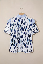 White polyester shirt with abstract blue brushstroke print, ruffled collar, and short sleeves.