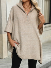 Apricot knit zip-neck poncho with short sleeves and asymmetrical hem, styled with black pants.