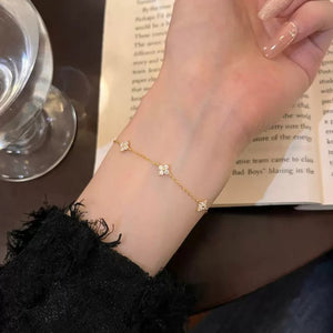 Gold delicate bracelet with four-leaf clover charms and clear stones.