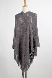 Dark gray crochet poncho with intricate openwork pattern and fringe detail.