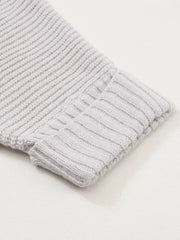 Light gray acrylic knit cardigan sleeve detail with ribbed cuff and textured knit.