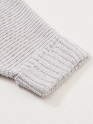 Light gray acrylic knit cardigan sleeve detail with ribbed cuff and textured knit.
