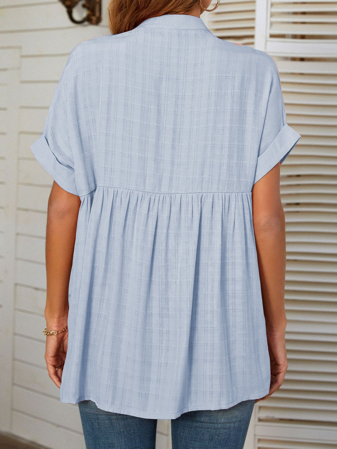 Light blue linen blend blouse with gathered yoke, short sleeves, and subtle plaid texture.