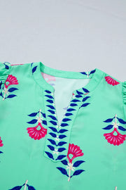 Embroidered floral v-neck blouse in mint green with flutter sleeves and blue leaf trim.