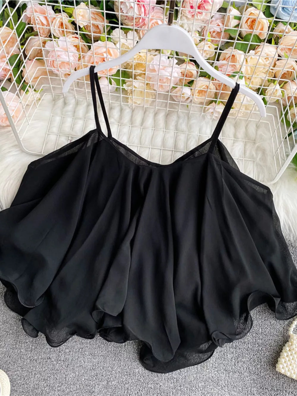 Black ruffled camisole with spaghetti straps and a flowy hem.
