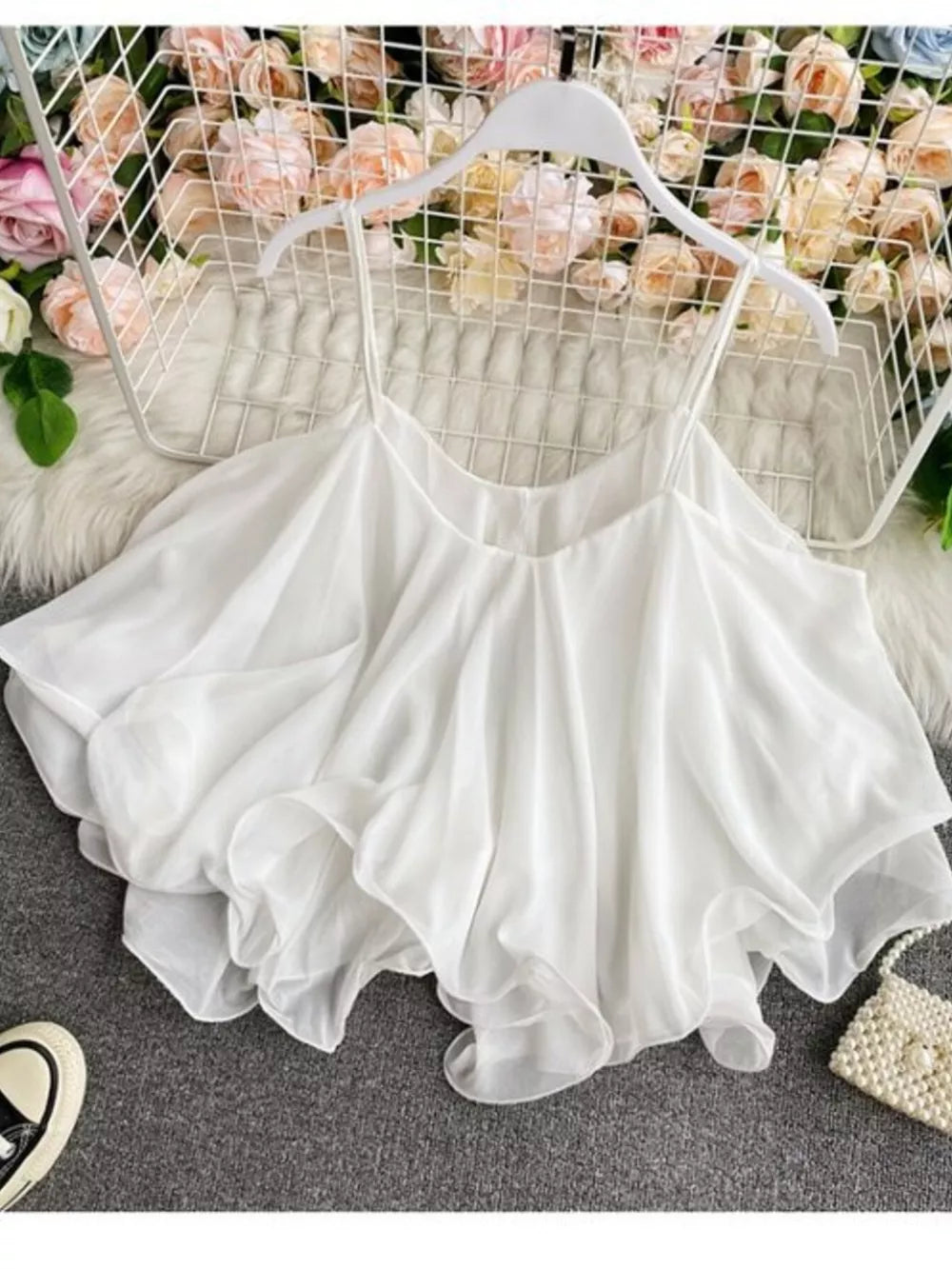 White ruffled camisole with spaghetti straps and a flowy hem.
