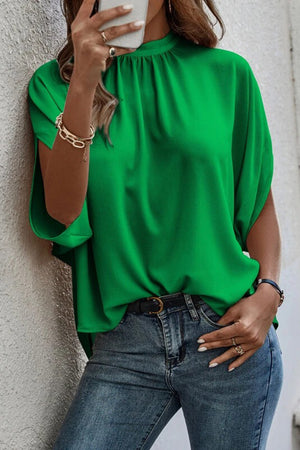 Keyhole back drape sleeve top in dark green with a high neckline and dolman sleeves.