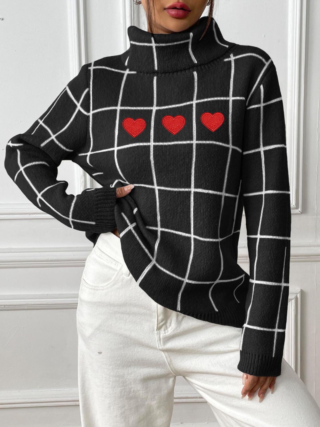 Black turtleneck sweater with white grid pattern and three red heart appliqués.