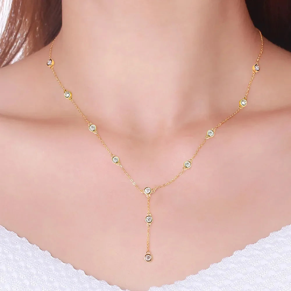 Gold lariat necklace with scattered moissanite stones and a drop pendant.