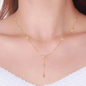 Gold lariat necklace with scattered moissanite stones and a drop pendant.