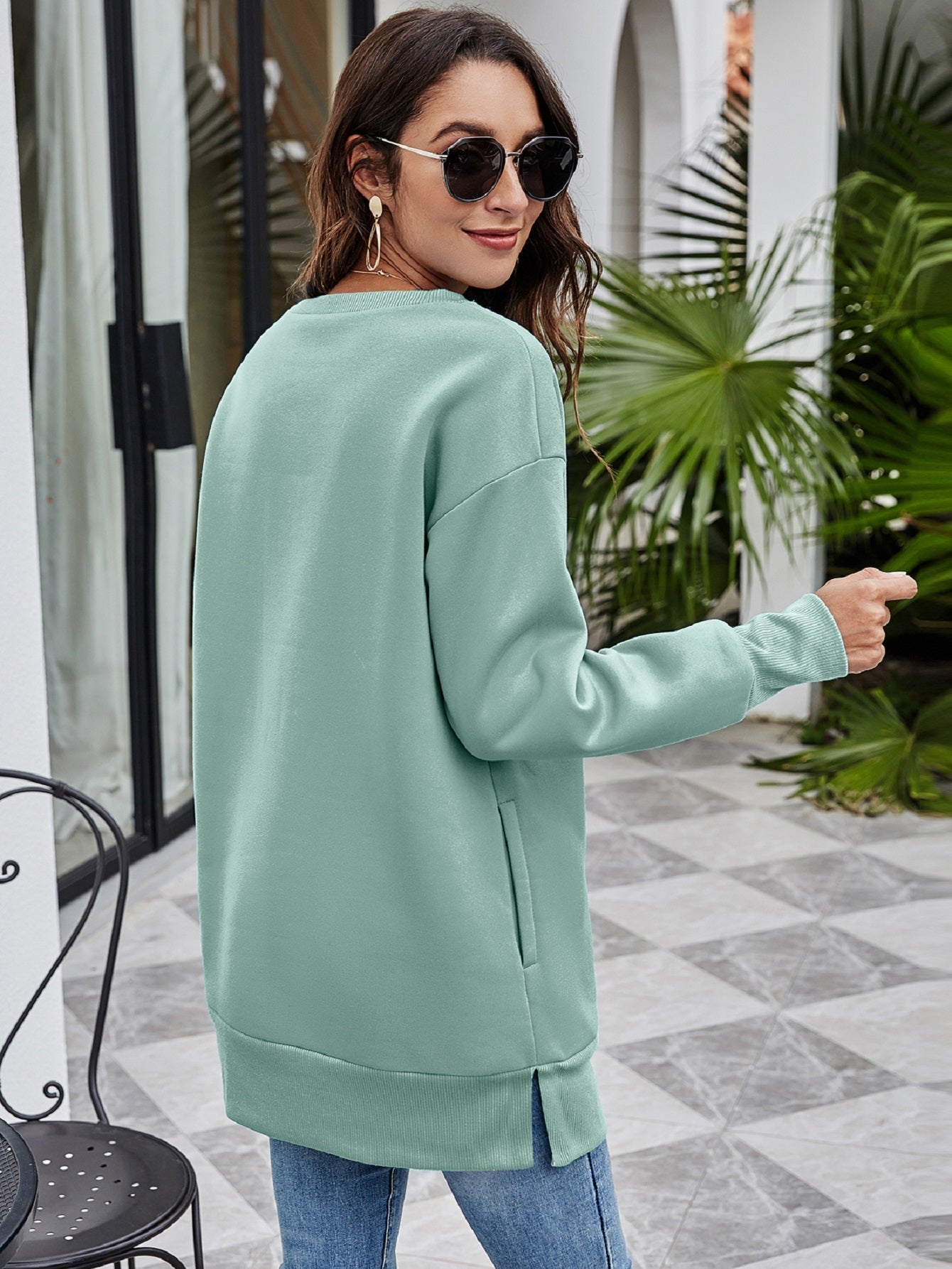 Sage green tunic sweatshirt with side pockets and split hem, styled with jeans.