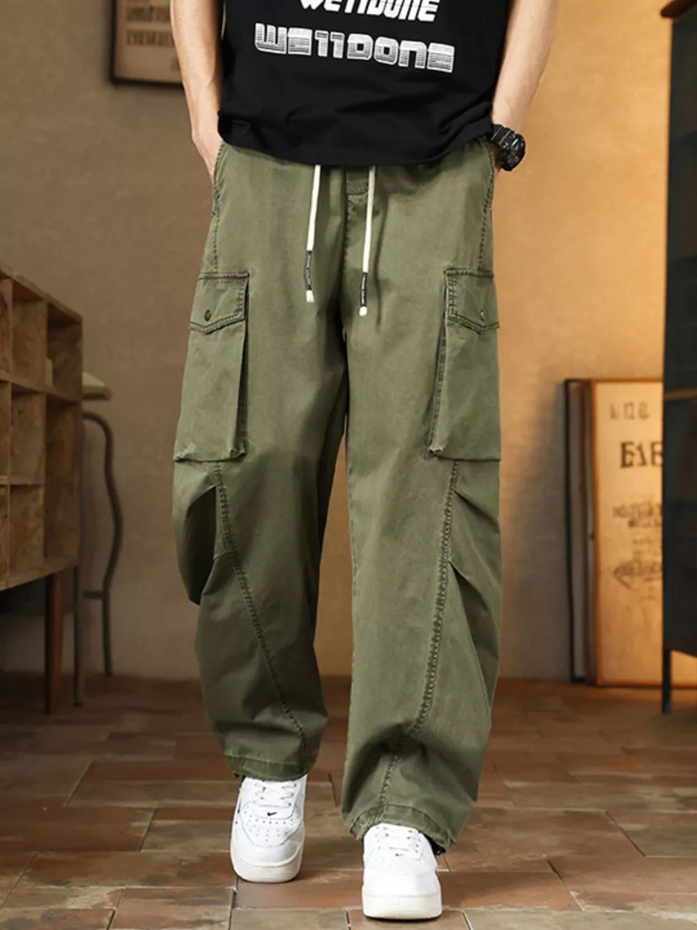 Men's green cargo pants with drawstring waist and button-down flap pockets.