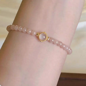 Gold-plated bracelet with blush pink beads and a central moonstone accent.