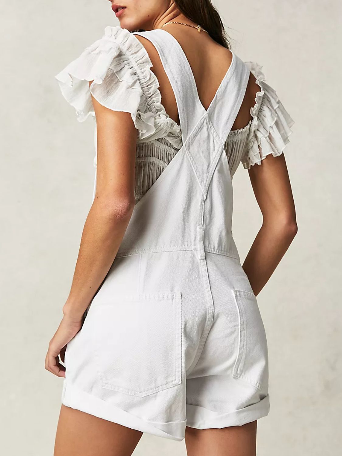 White denim short overalls with cuffed hems and ruffled sleeves.