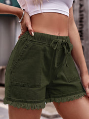 Army green denim shorts with frayed hem, drawstring waist, and utility pockets.