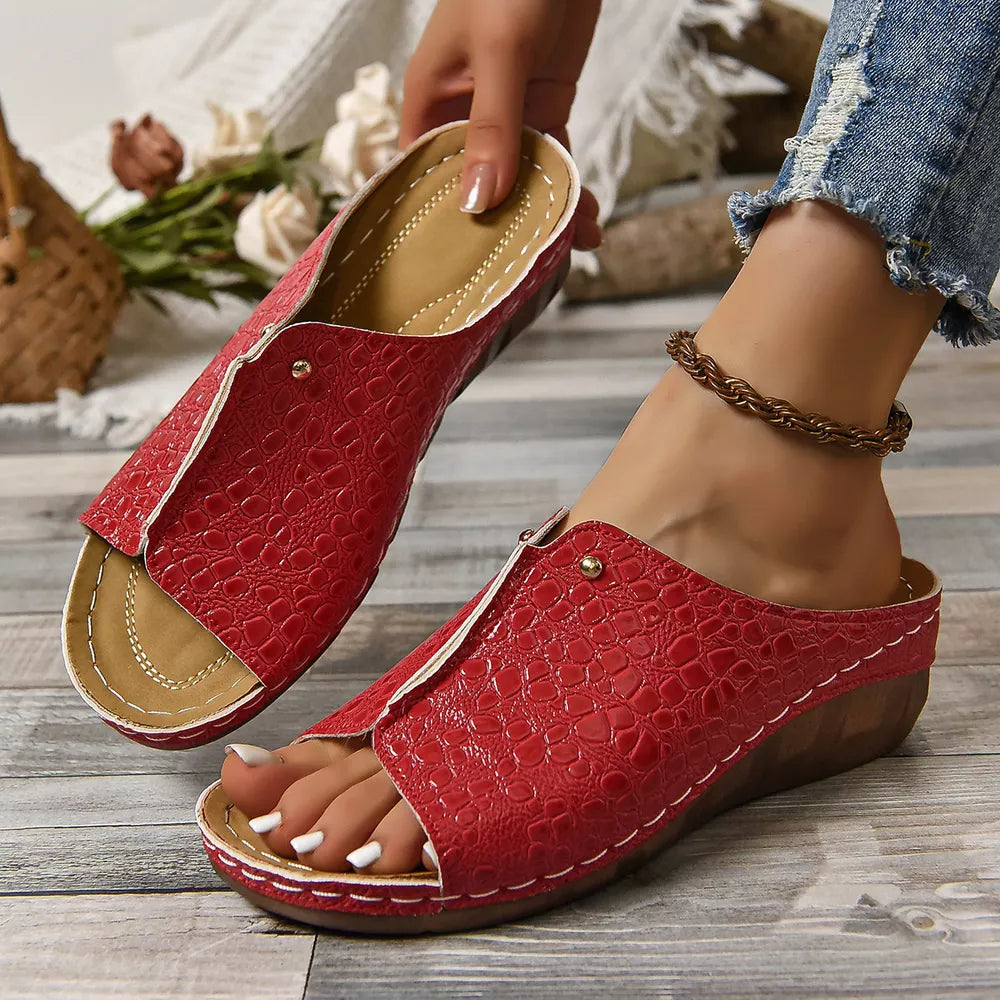 Red glossy crocodile-embossed wedge sandals with open toe and white stitching detail.