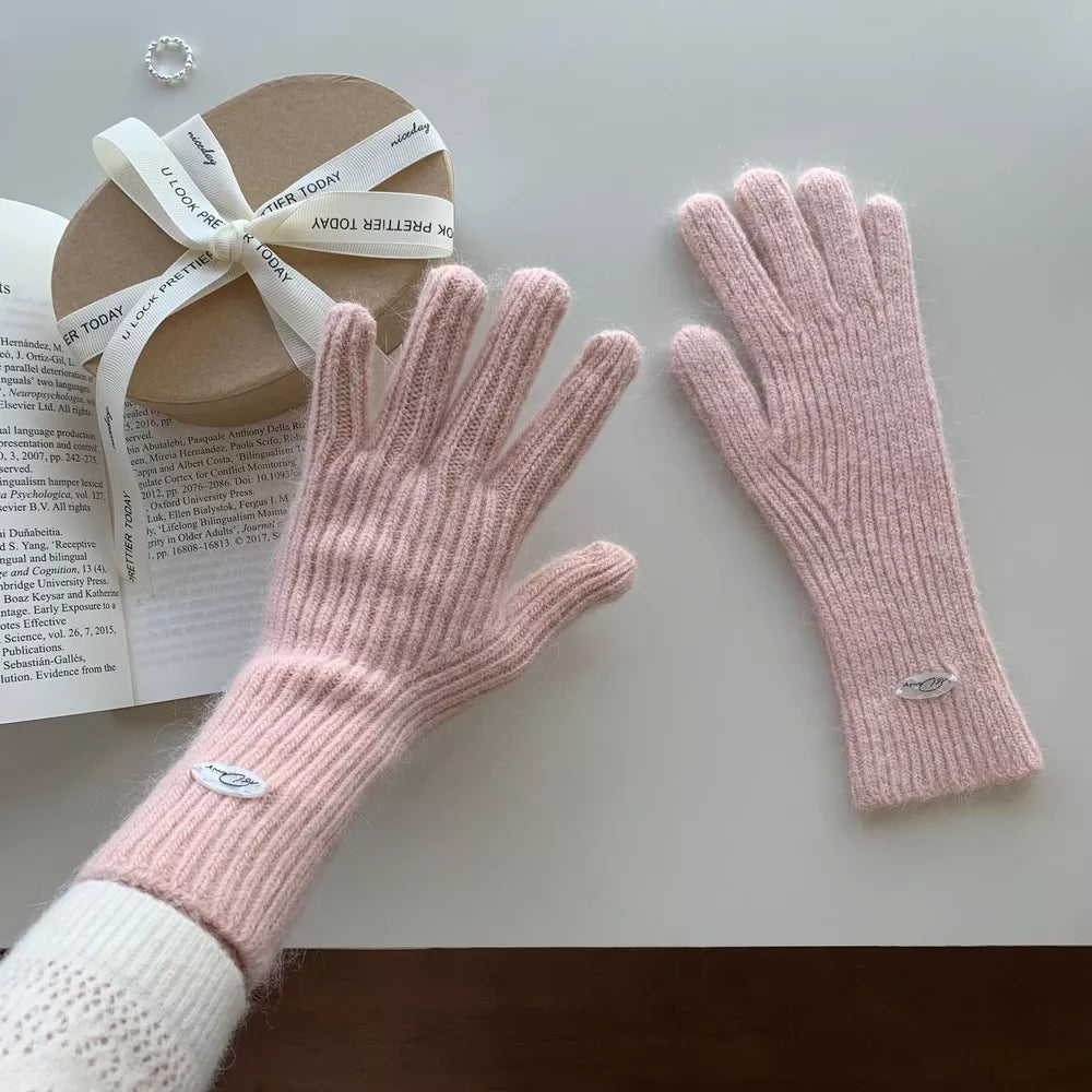 Blush pink ribbed knit touchscreen gloves with a soft fuzzy texture and small logo detail.