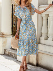 Blue midi dress with daisy print, tie-front, tiered skirt, and short sleeves.
