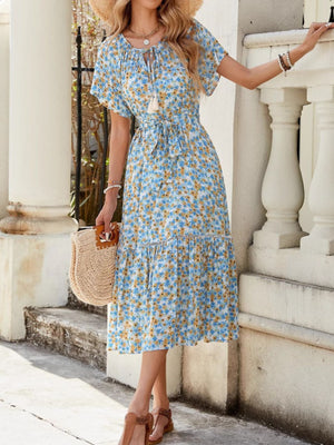 Blue midi dress with daisy print, tie-front, tiered skirt, and short sleeves.