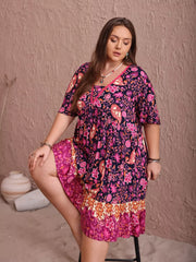 Plus-size navy floral flutter dress with ruched bodice and tiered hem.