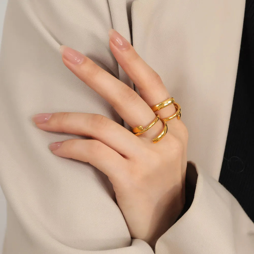 Gold sculptural spiral steel ring with open ends on a woman's hand.
