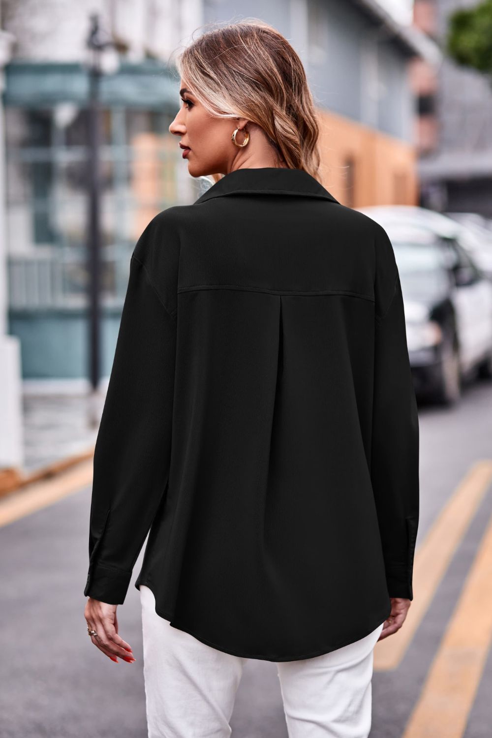 Black oversized utility shirt with pleated back detail and button cuffs.