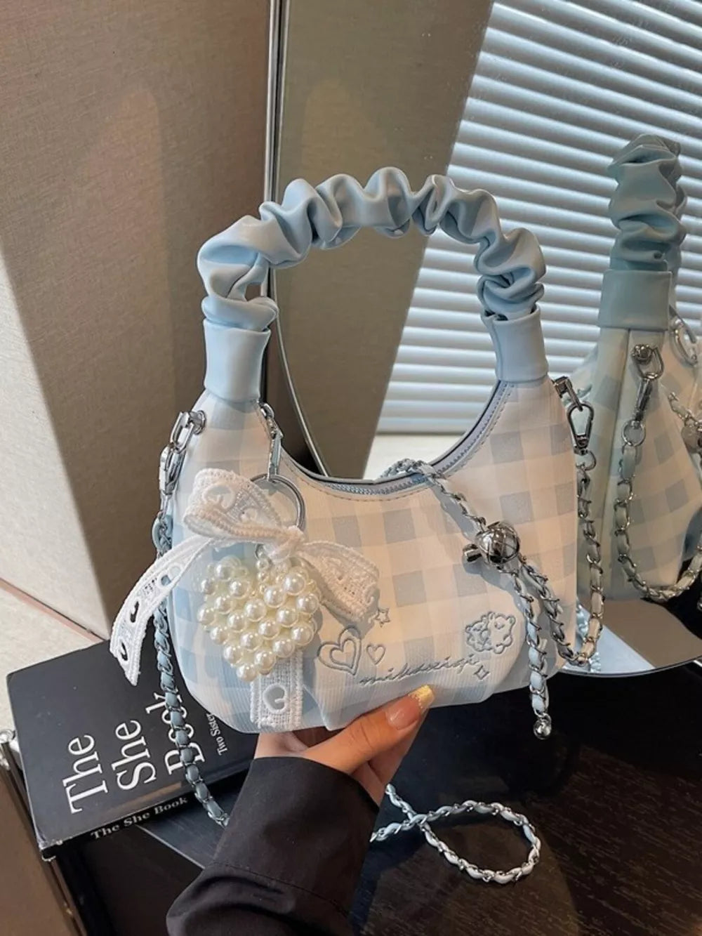 Charming mini crossbody bag in light blue gingham with ruched handle and pearl heart charm.
