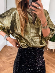 Gold crinkled blouse with 3/4 sleeves and notched V-neck, styled with a sequin skirt.