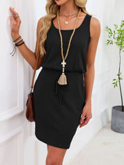 Sleeveless black waffle-knit drawstring dress with tassel detail and scoop neckline.