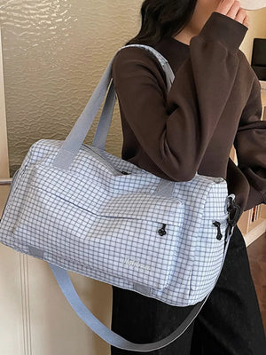 Elegant plaid travel bag with versatile straps and front pocket detail.