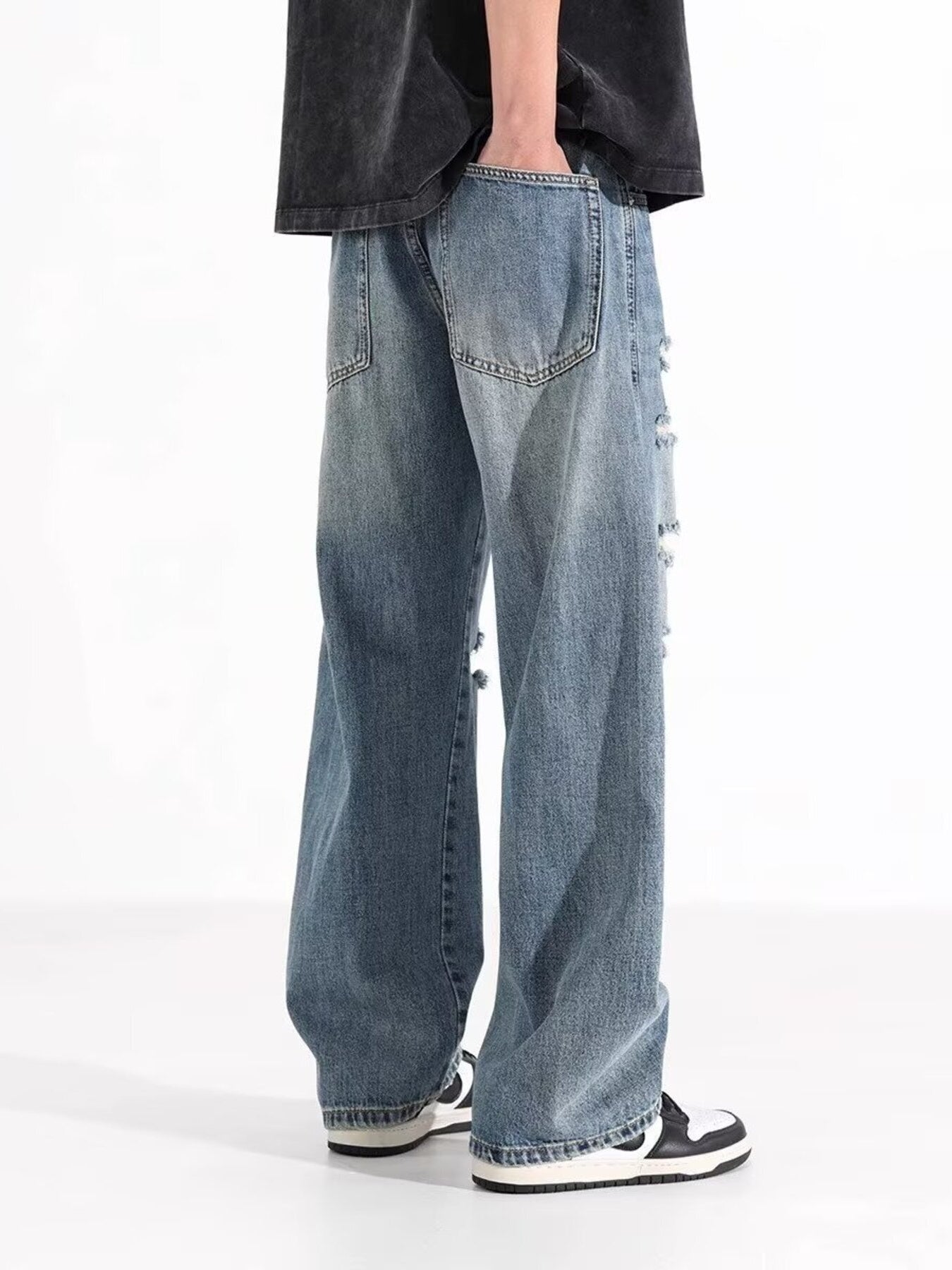 Men's washed blue distressed wide-leg jeans with ripped details.