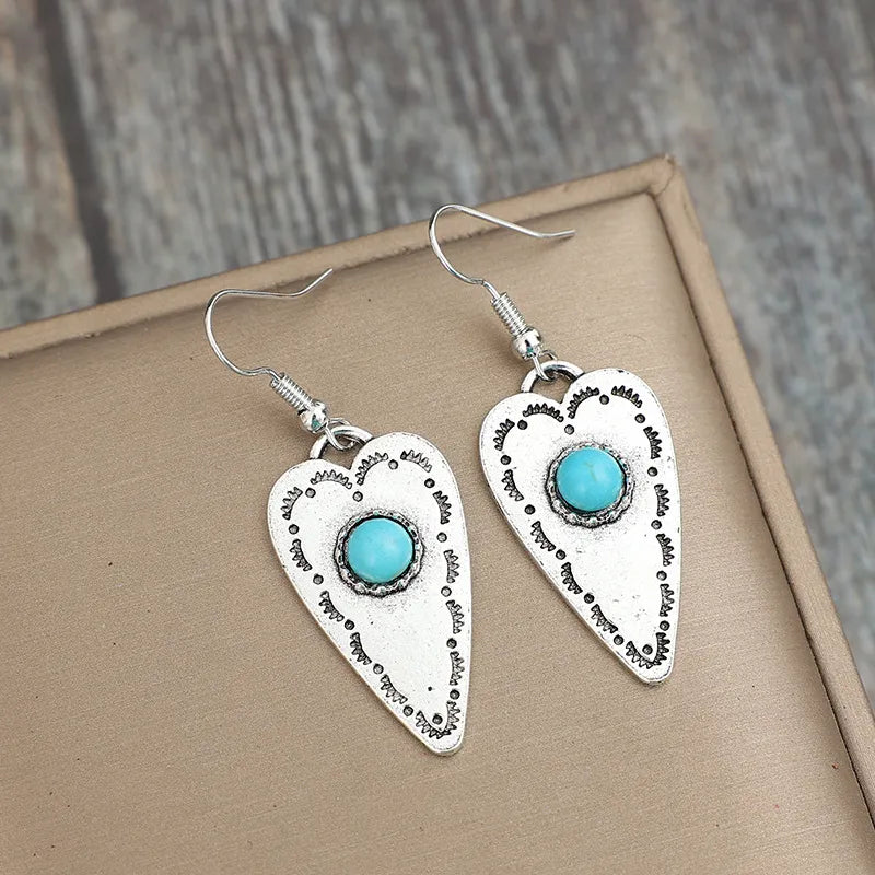 Silver heart-shaped earrings with turquoise stones and decorative etching.