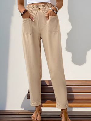 Tan linen blend trousers with gathered waist, button detail, and cuffed hem.