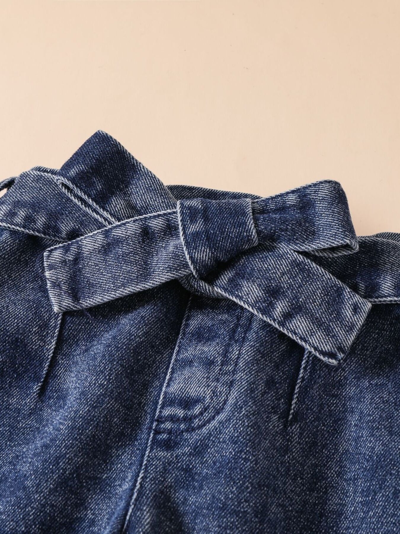 Acid-wash denim jeans with a tie waist detail.