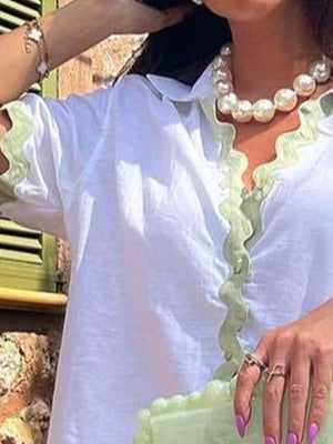 White collared pajama top with green wavy trim detail and short sleeves.