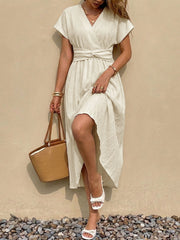 Beige cotton blend midi dress with V-neck, short sleeves, and twisted knot waist detail.