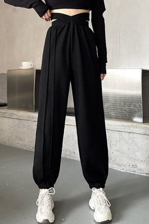 Black pleated waistline joggers with a crisscross detail and elastic cuffs.