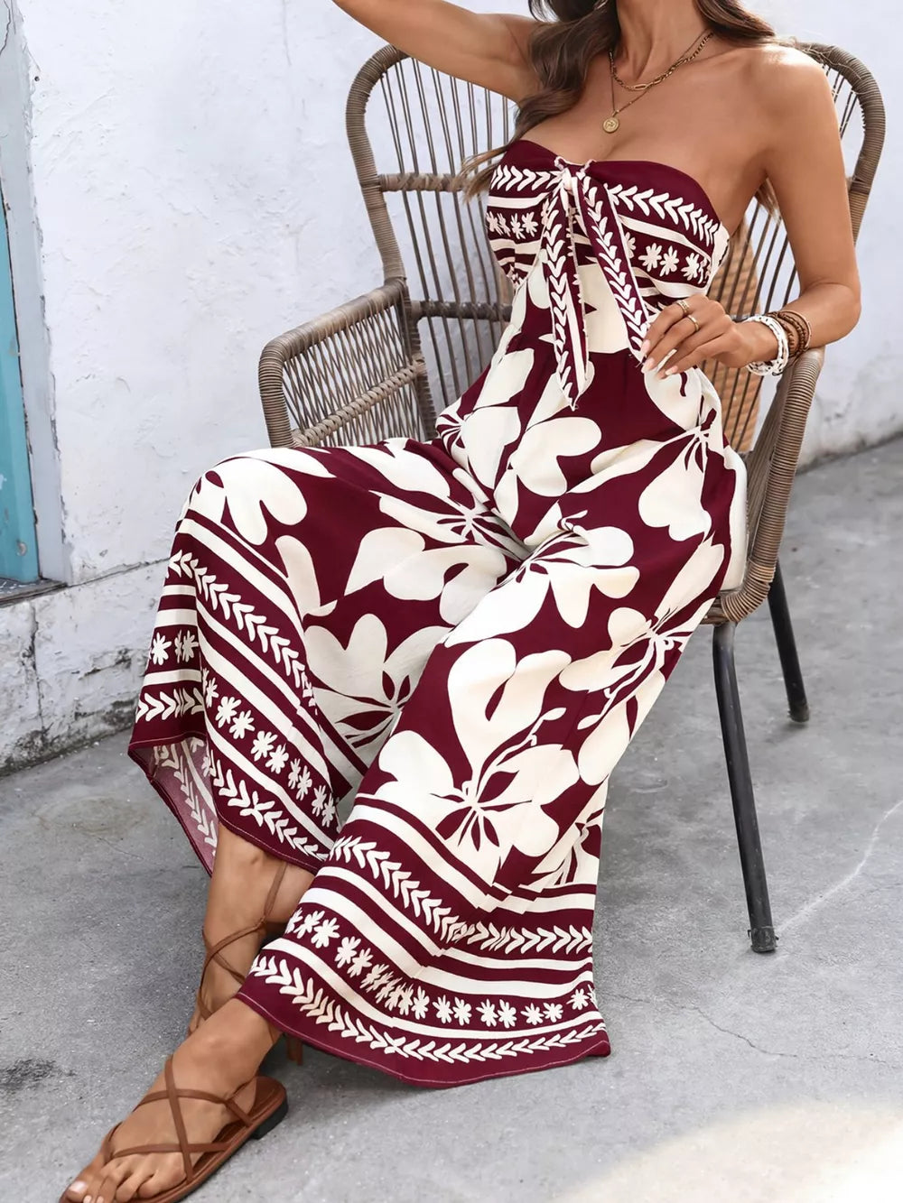 Burgundy floral tie-front strapless wide-leg romper with a draped silhouette.