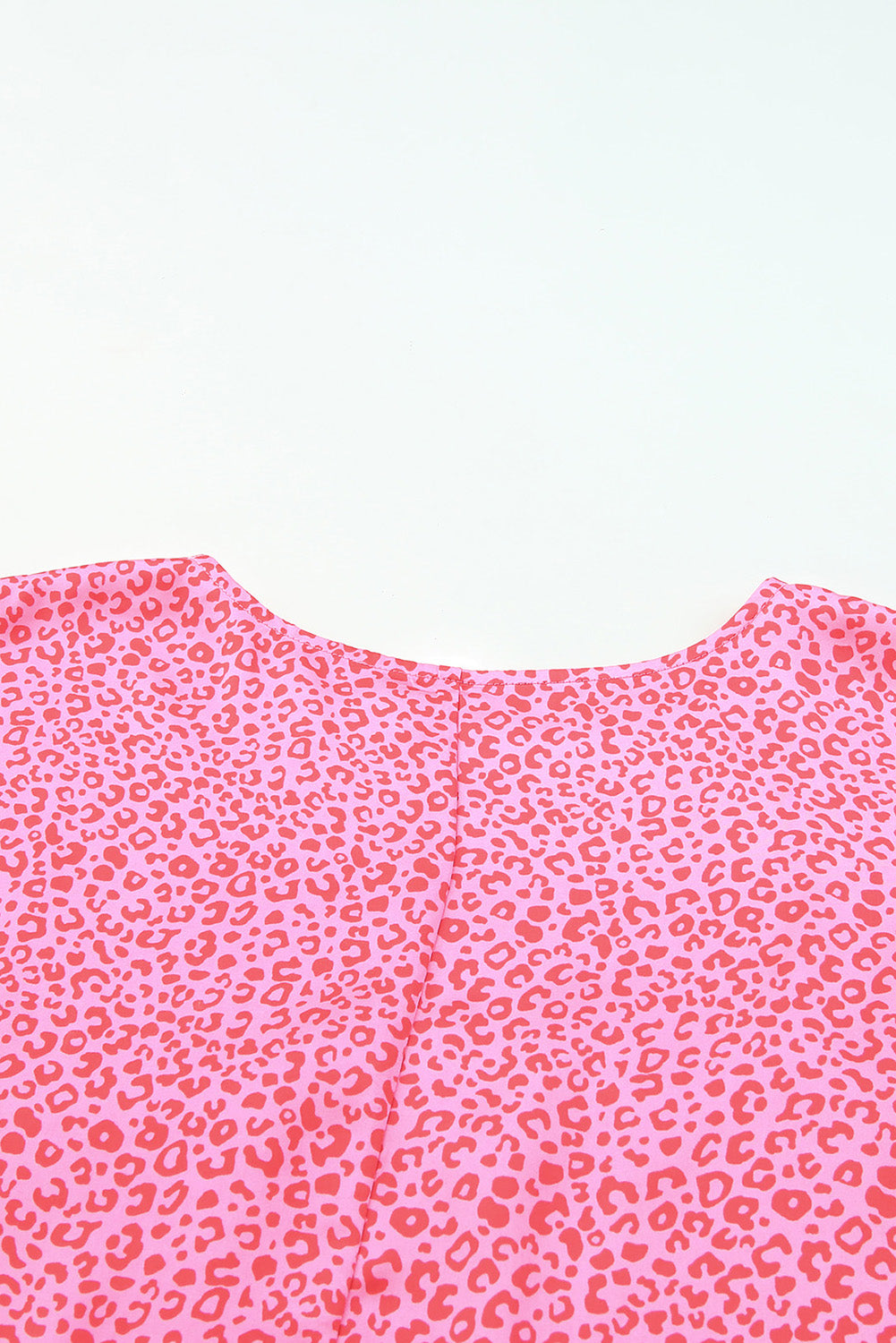 Pink leopard print blouse with smocked sleeves and crew neck detail.