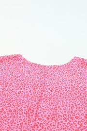 Pink leopard print blouse with smocked sleeves and crew neck detail.