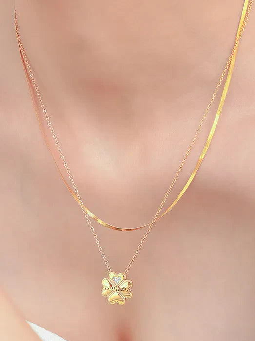 Gold layered necklace with a clover charm featuring a small diamond accent.