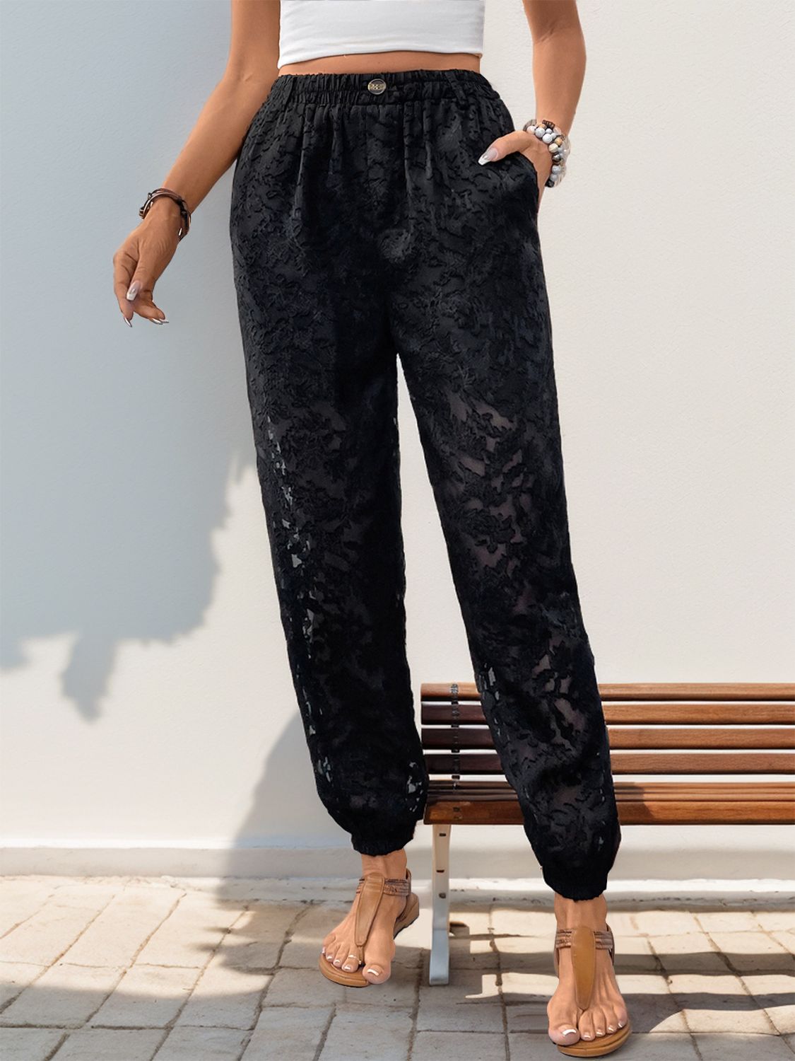 Black lace joggers with elastic waist and cuffed ankles, featuring a subtle floral pattern.