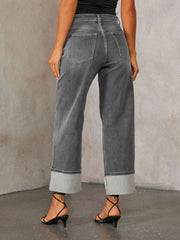 Dark wash denim jeans with wide legs and cuffed hems.
