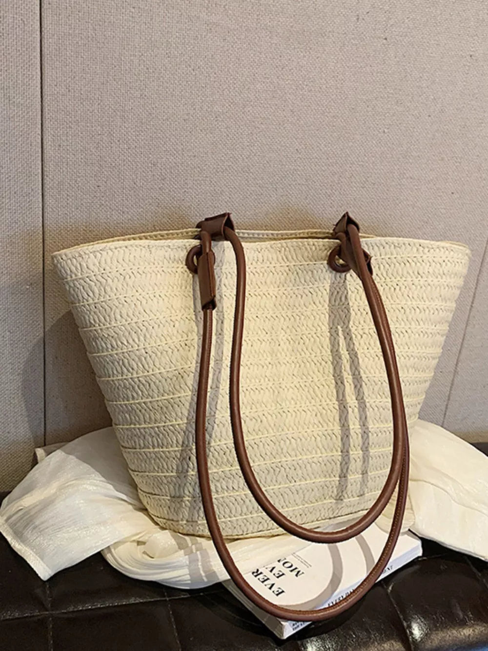 Natural straw woven large shoulder bag in beige with brown leather straps.