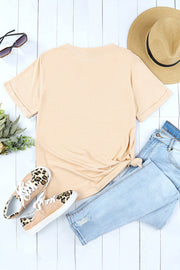 Sand crop top graphic tee with rolled sleeves and a knotted hem, styled with jeans and leopard print sneakers.