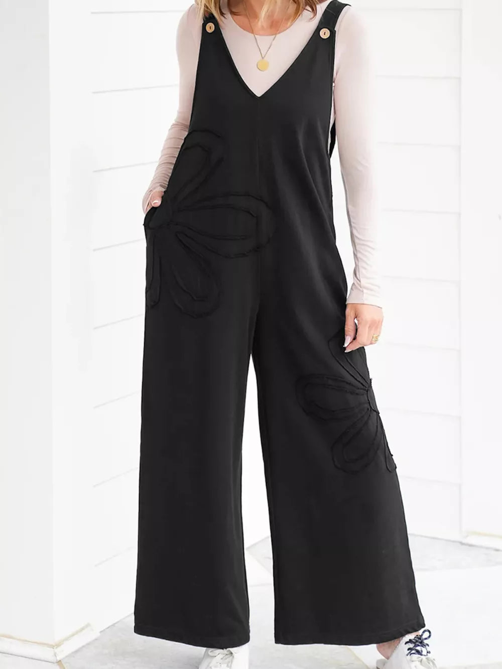 Black cotton wide-leg maternity romper with floral appliqué detail and button straps.